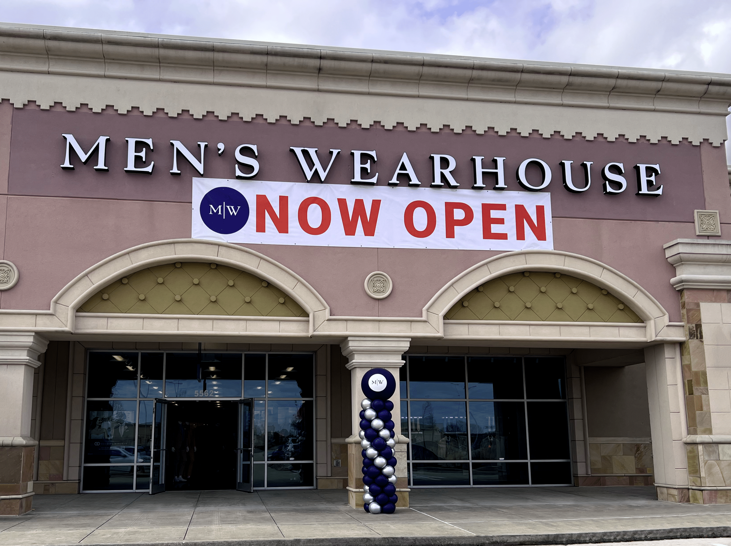Storefront reading "Men's Wearhouse Now Open"